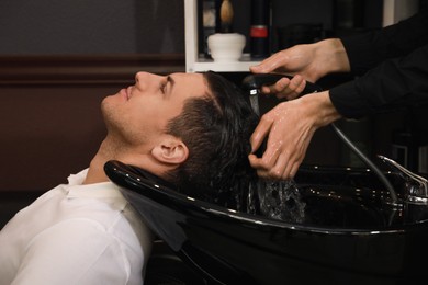 Professional hairdresser washing client's hair at sink in salon, closeup Photo of Professional hairdresser washing client's hair at sink in salon, closeup