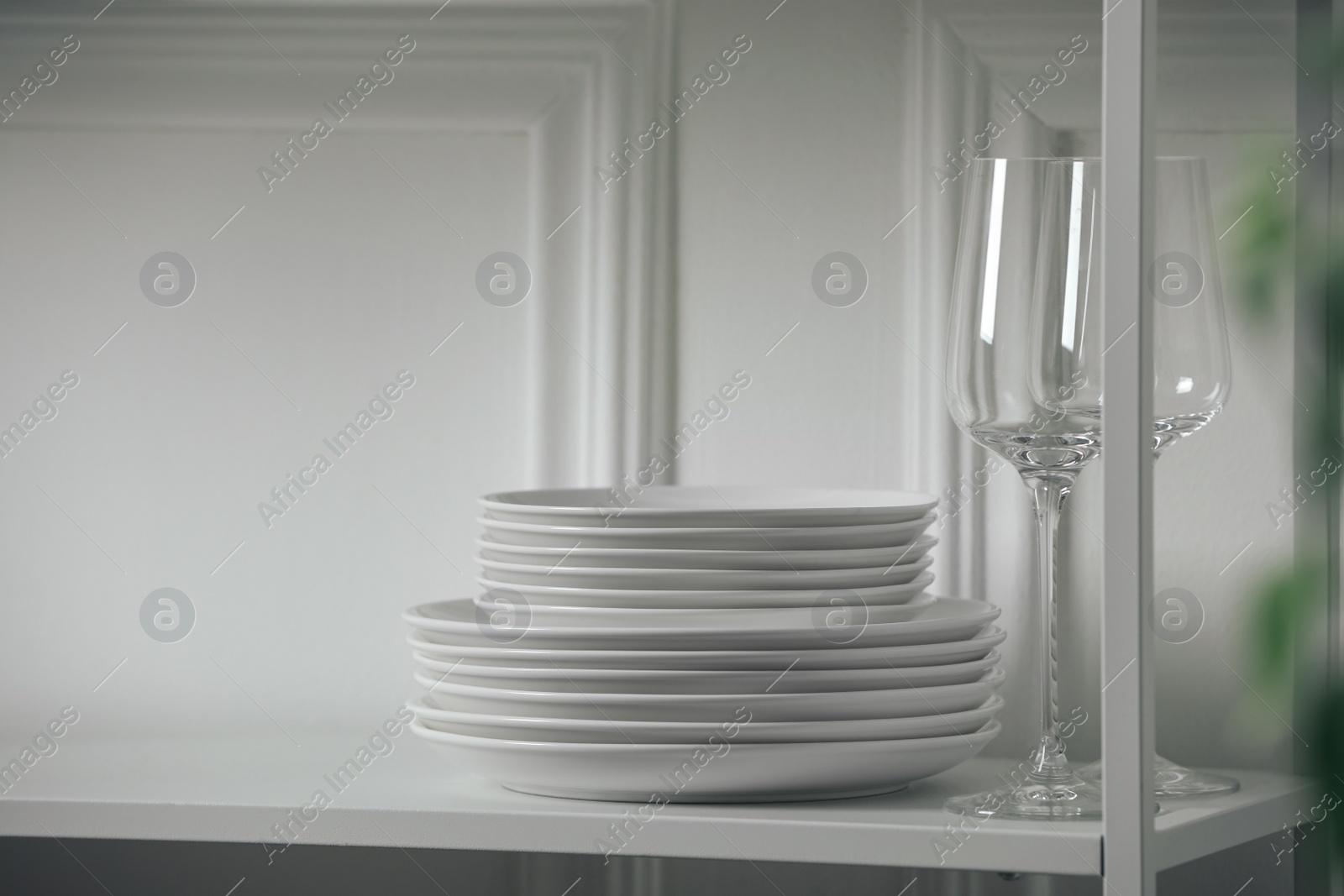 Stacked clean dishes and glasses on table indoors Photo of Stacked clean dishes and glasses on table indoors