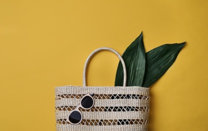 Stylish straw bag and sunglasses on yellow background, flat lay. Summer accessories Photo of Stylish straw bag and sunglasses on yellow background, flat lay. Summer accessories