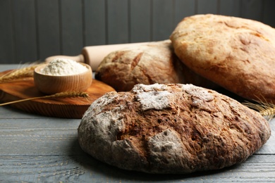 Loaf of delicious fresh bread on grey wooden table Photo of Loaf of delicious fresh bread on grey wooden table