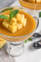 Delicious panna cotta with mango coulis and fresh fruit pieces on table, closeup Photo of Delicious panna cotta with mango coulis and fresh fruit pieces on table, closeup