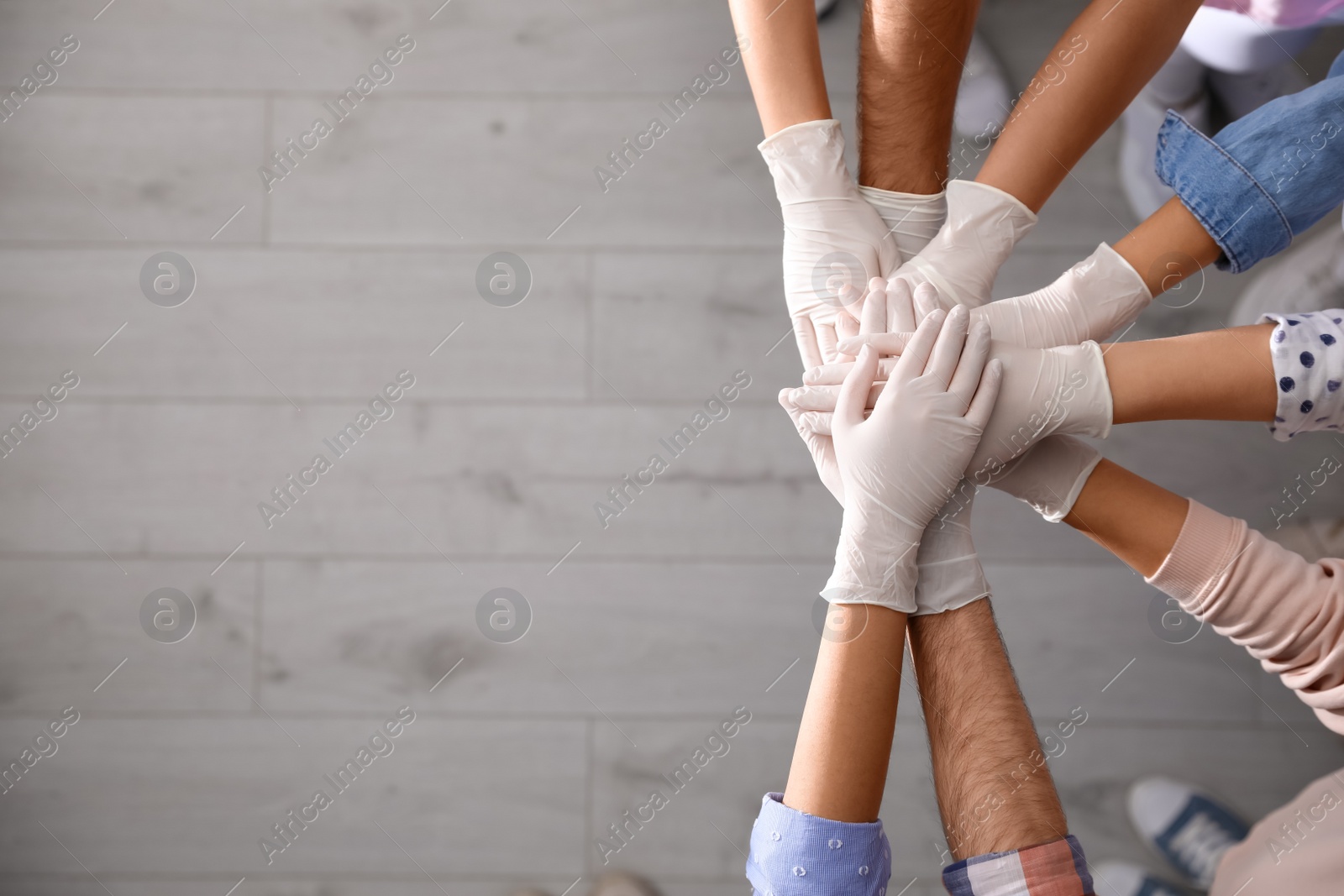 People in white medical gloves stacking hands indoors, top view. Space for text Photo of People in white medical gloves stacking hands indoors, top view. Space for text