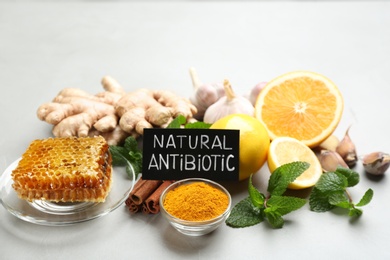 Different fresh products and card with phrase Natural Antibiotic on grey table Photo of Different fresh products and card with phrase Natural Antibiotic on grey table