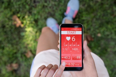 Young woman using fitness app on smartphone outdoors, top view Photo of Young woman using fitness app on smartphone outdoors, top view