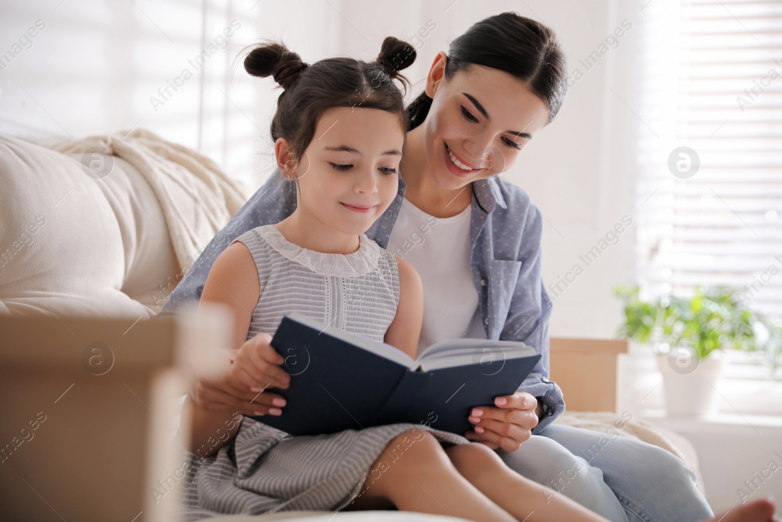 Little girl with mother reading fairy tale in living room Photo of Little girl with mother reading fairy tale in living room