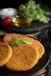 Photo of Delicious fried breaded cutlets with basil on wooden table, closeup