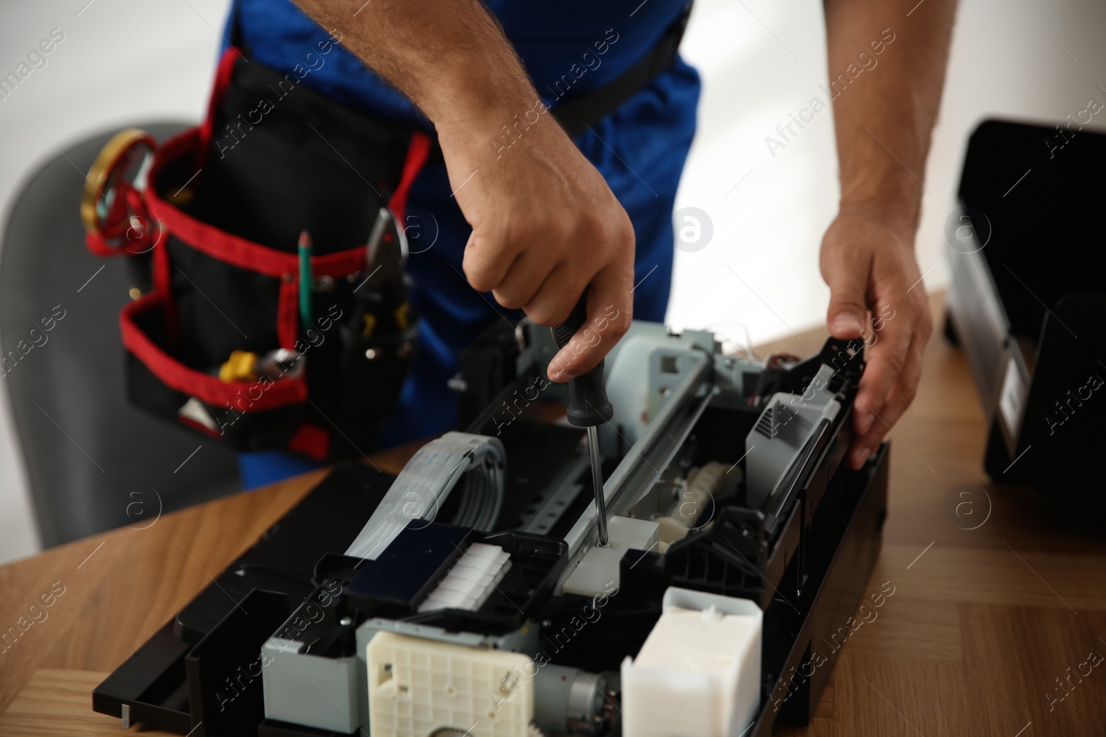 Repairman with screwdriver fixing modern printer indoors, closeup Photo of Repairman with screwdriver fixing modern printer indoors, closeup