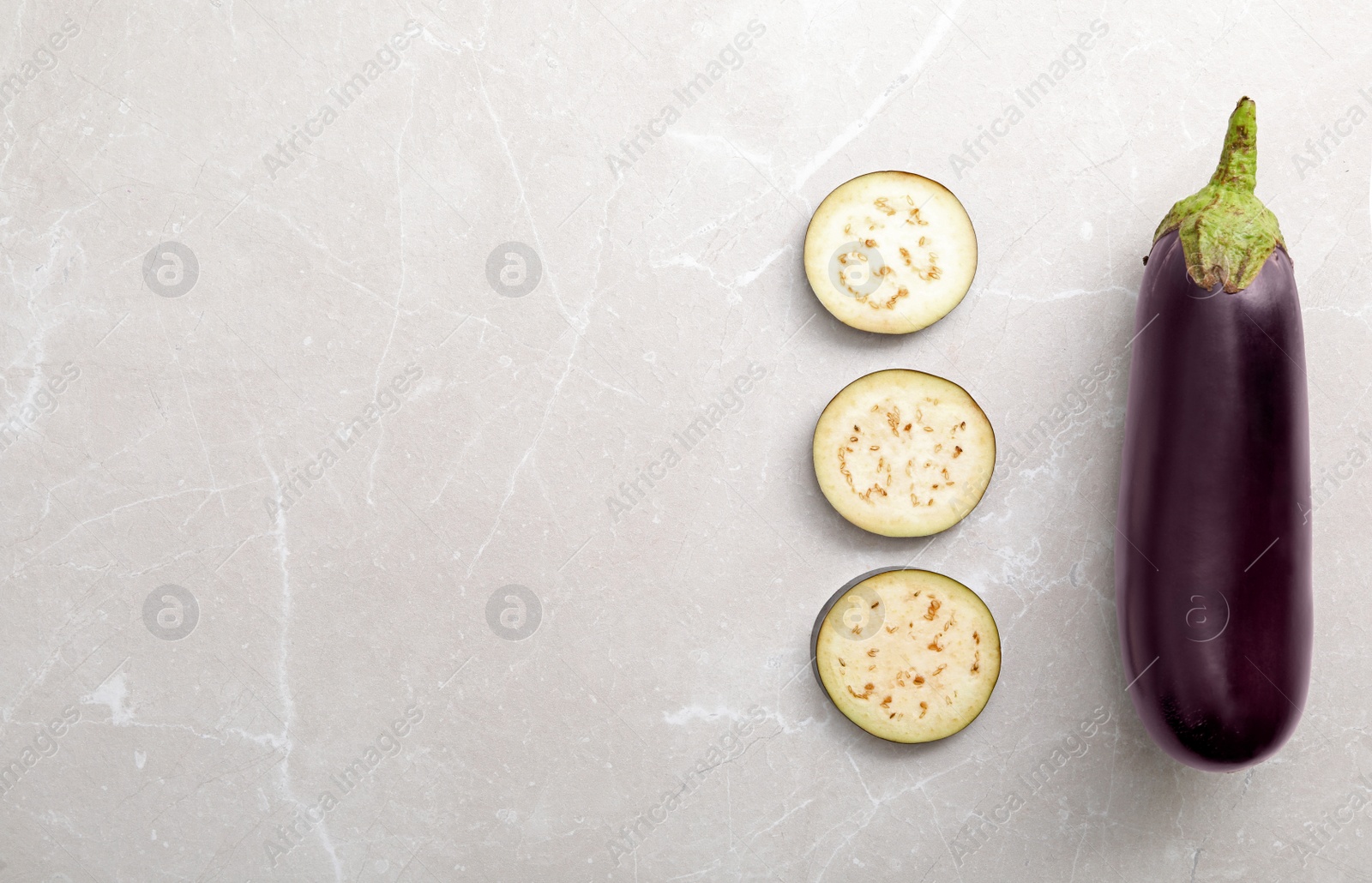 Cut and whole raw ripe eggplants on light table, flat lay. Space for text Photo of Cut and whole raw ripe eggplants on light table, flat lay. Space for text