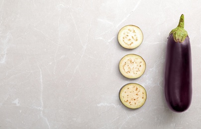 Photo of Cut and whole raw ripe eggplants on light table, flat lay. Space for text