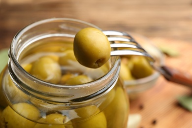 Glass jar of pickled olives and fork, closeup Photo of Glass jar of pickled olives and fork, closeup