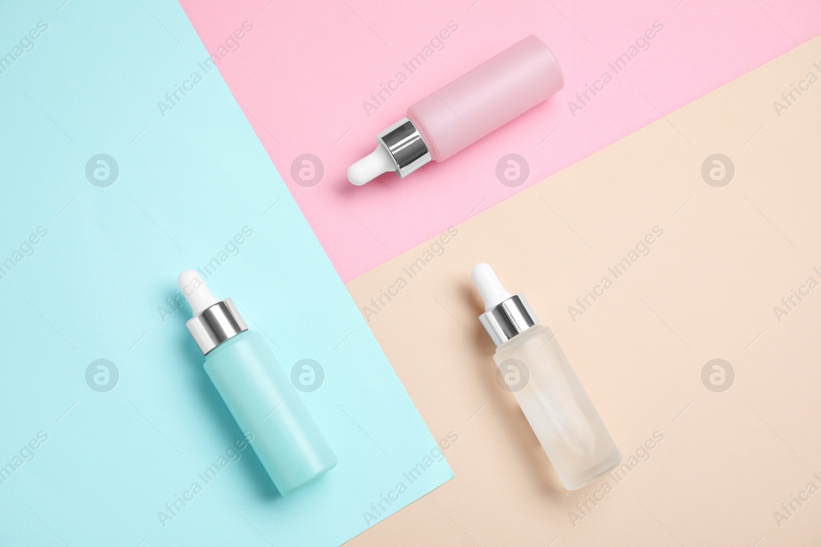 Bottles of essential oils on color background, flat lay Photo of Bottles of essential oils on color background, flat lay