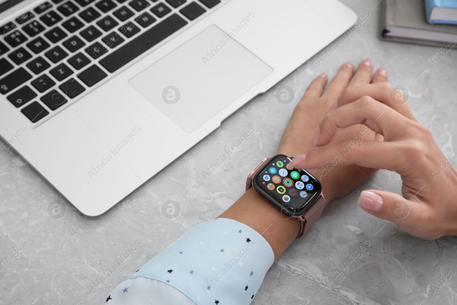 MYKOLAIV, UKRAINE - SEPTEMBER 19, 2019: Woman using Apple Watch at grey table, closeup Image of MYKOLAIV, UKRAINE - SEPTEMBER 19, 2019: Woman using Apple Watch at grey table, closeup