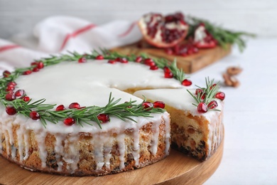 Traditional Christmas cake decorated with rosemary and pomegranate seeds on white table, closeup Photo of Traditional Christmas cake decorated with rosemary and pomegranate seeds on white table, closeup