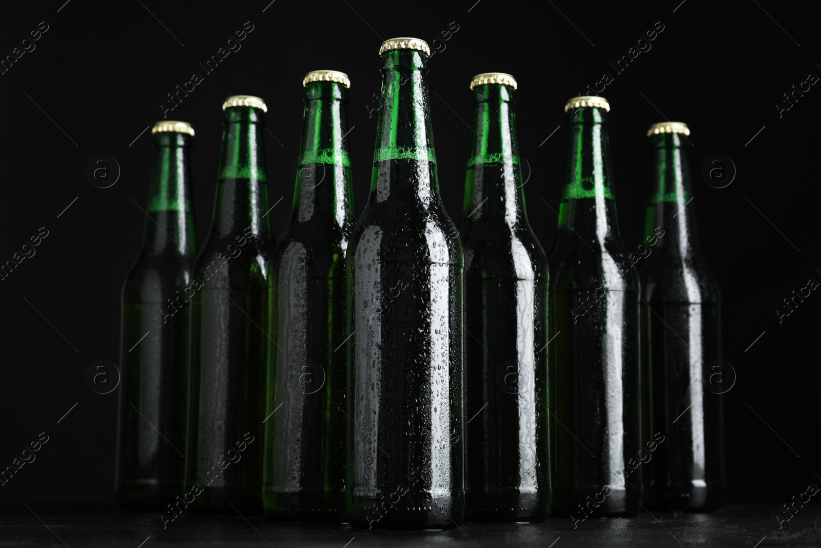 Photo of Glass bottles of beer on table against black background