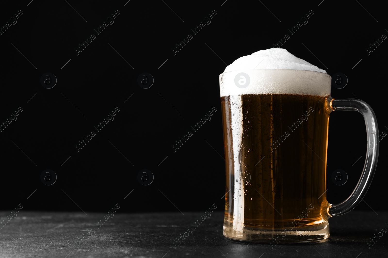 Cold tasty beer on grey table against dark background. Space for text Photo of Cold tasty beer on grey table against dark background. Space for text