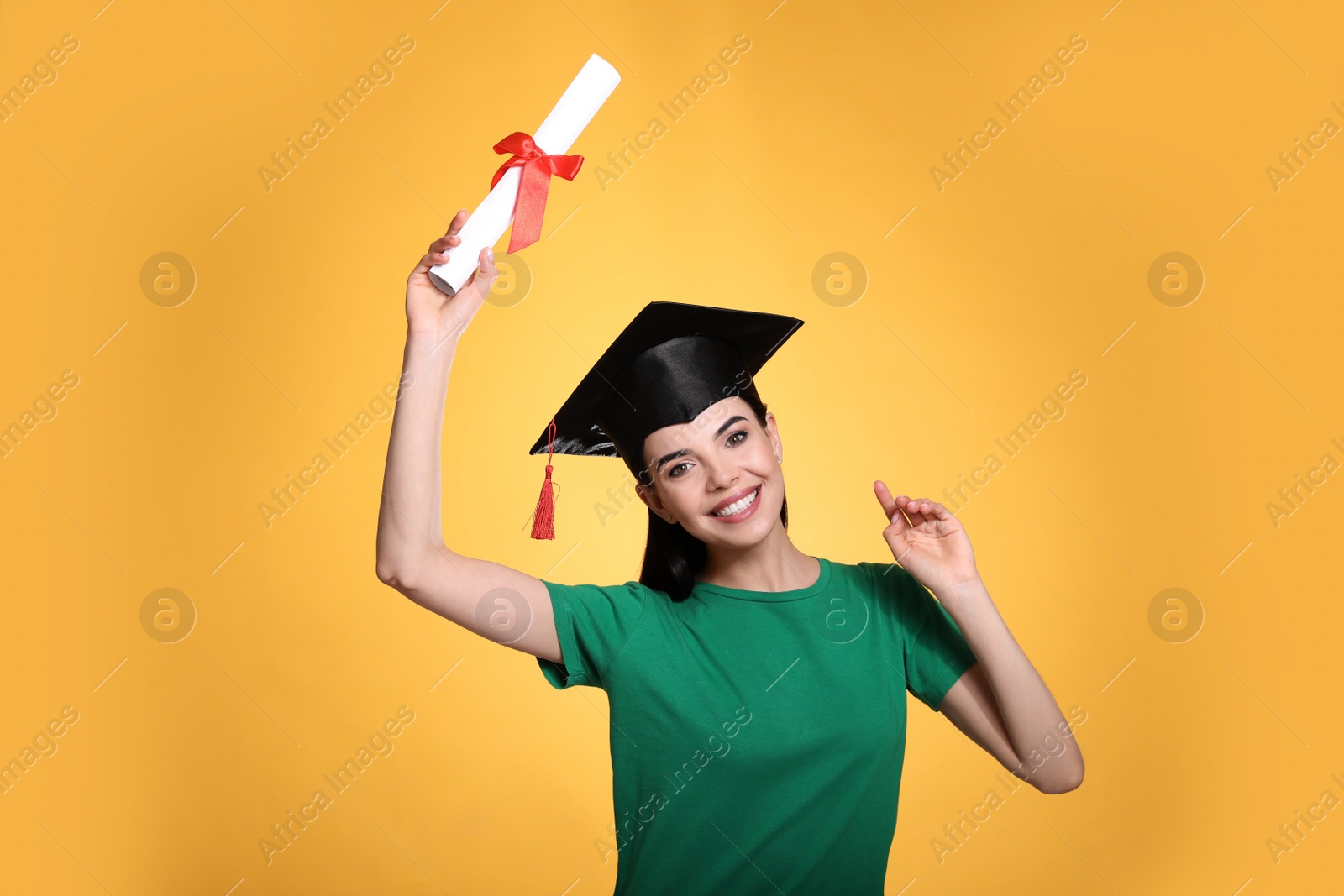 Happy student with graduation hat and diploma on yellow background Photo of Happy student with graduation hat and diploma on yellow background