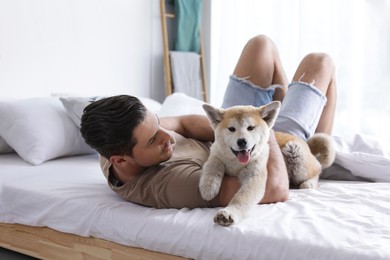 Happy man with his cute Akita Inu puppy at home Image of Happy man with his cute Akita Inu puppy at home