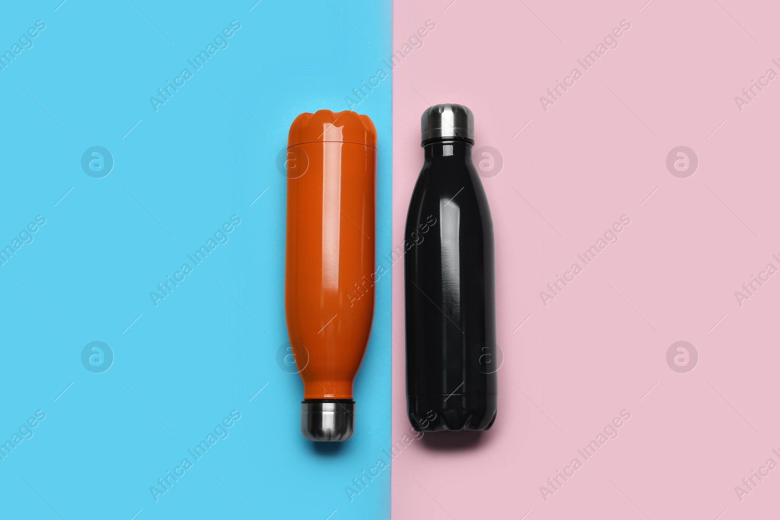 Modern thermo bottles on color background, flat lay Photo of Modern thermo bottles on color background, flat lay