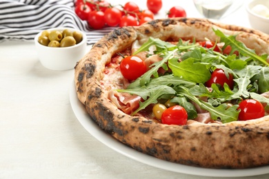 Tasty pizza with meat and arugula on white table, closeup Photo of Tasty pizza with meat and arugula on white table, closeup