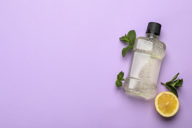 Mouthwash, mint and lemon on violet background, flat lay. Space for text Photo of Mouthwash, mint and lemon on violet background, flat lay. Space for text