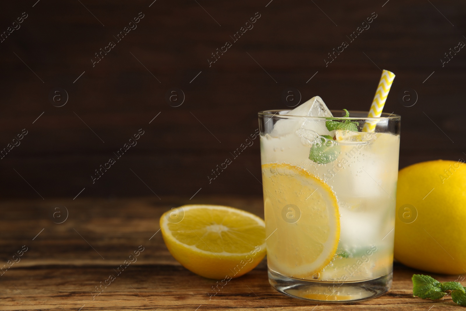 Cool freshly made lemonade in glass on wooden table. Space for text Photo of Cool freshly made lemonade in glass on wooden table. Space for text