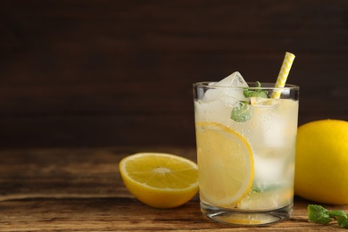 Cool freshly made lemonade in glass on wooden table. Space for text Photo of Cool freshly made lemonade in glass on wooden table. Space for text