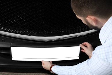 Man installing vehicle registration plate outdoors, closeup. Mockup for design Photo of Man installing vehicle registration plate outdoors, closeup. Mockup for design