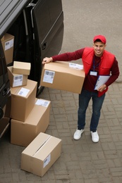 Courier with clipboard and parcel near delivery van outdoors, above view Photo of Courier with clipboard and parcel near delivery van outdoors, above view