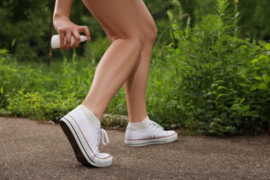Woman applying insect repellent onto leg in park, closeup. Tick bites prevention Photo of Woman applying insect repellent onto leg in park, closeup. Tick bites prevention