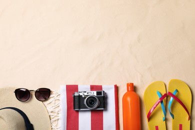 Beach towel, hat, sunglasses, camera, sunscreen and flip flops on sand, flat lay. Space for text Photo of Beach towel, hat, sunglasses, camera, sunscreen and flip flops on sand, flat lay. Space for text