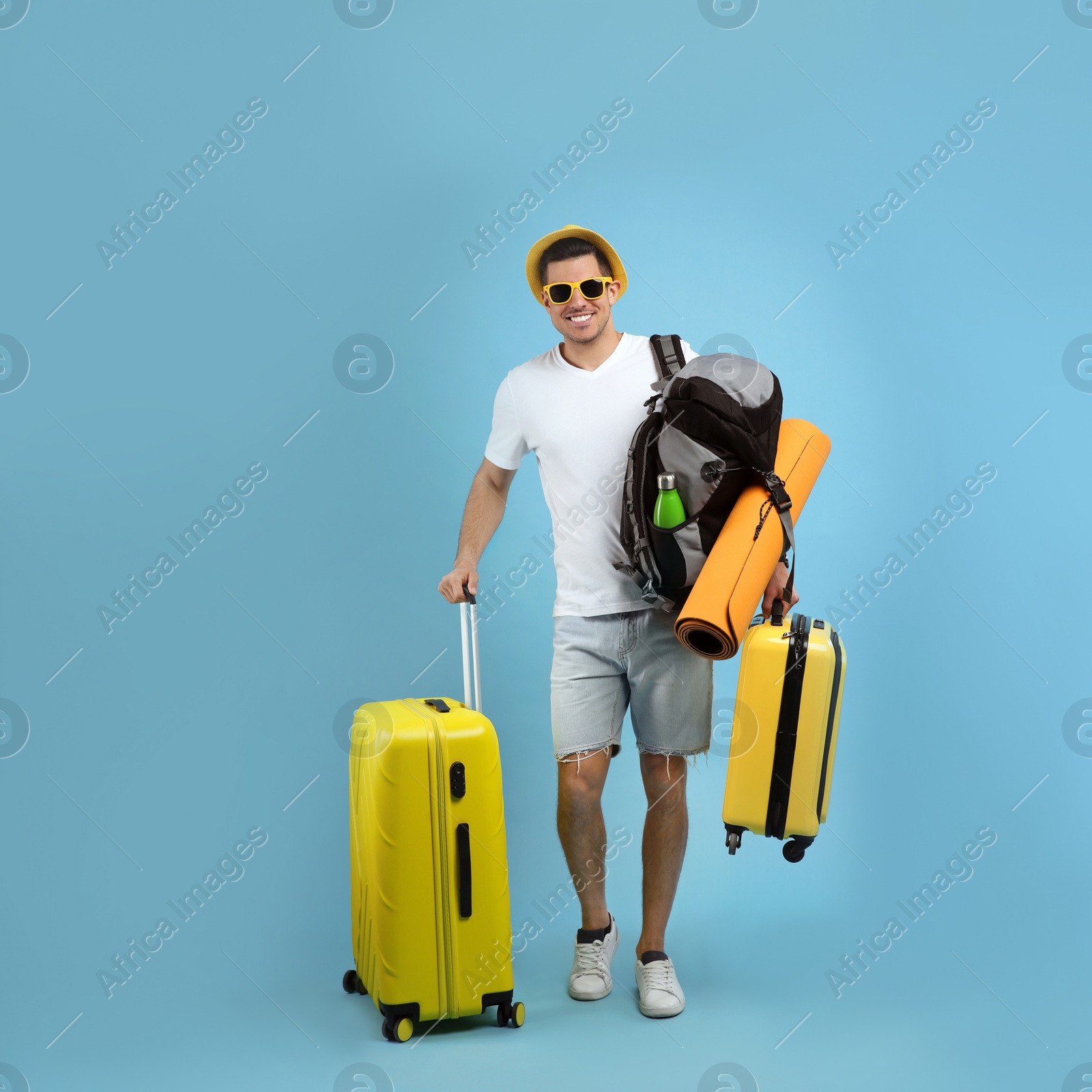 Photo of Male tourist with travel backpack and suitcases on turquoise background