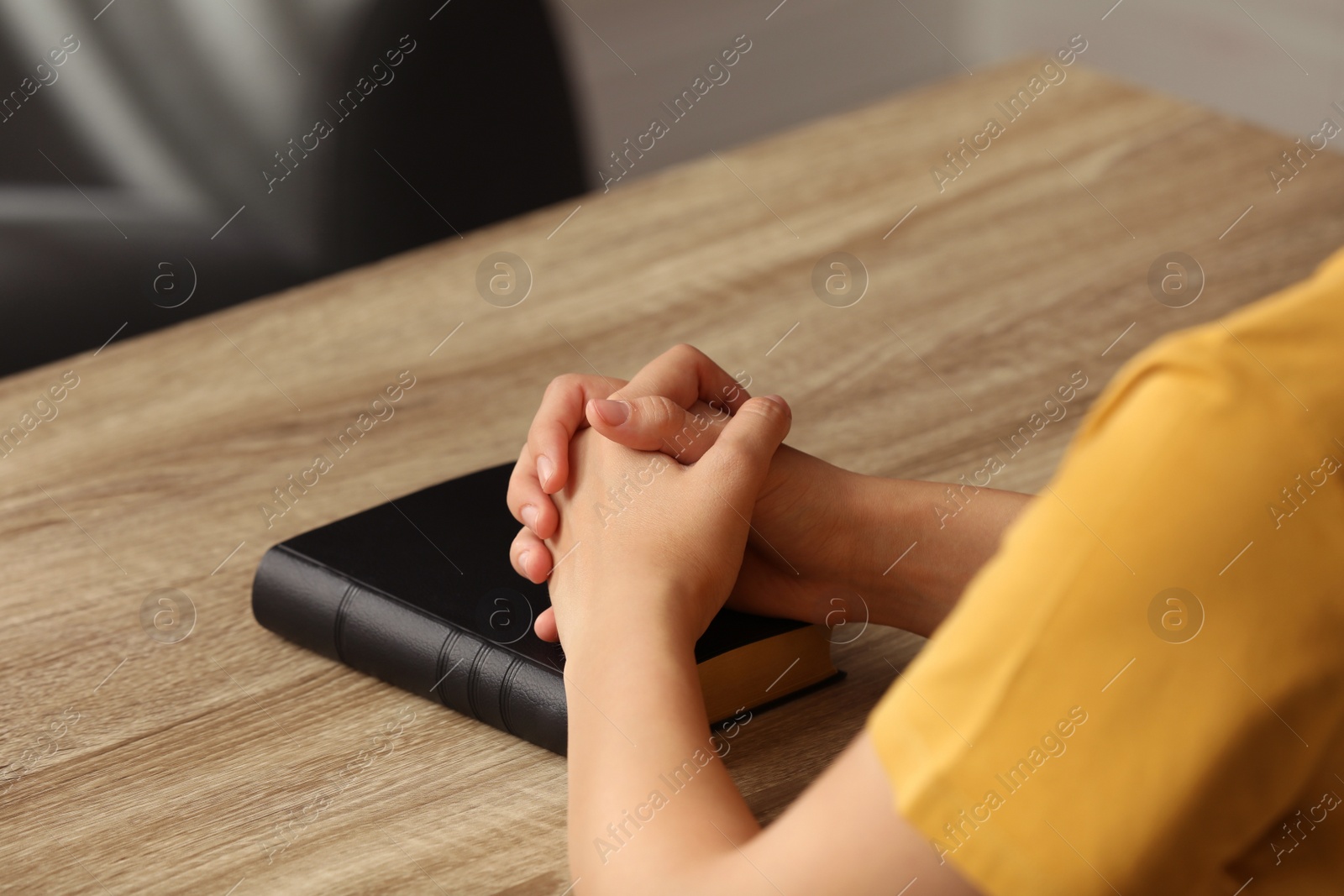 Religious woman praying over Bible at wooden table indoors, closeup Photo of Religious woman praying over Bible at wooden table indoors, closeup