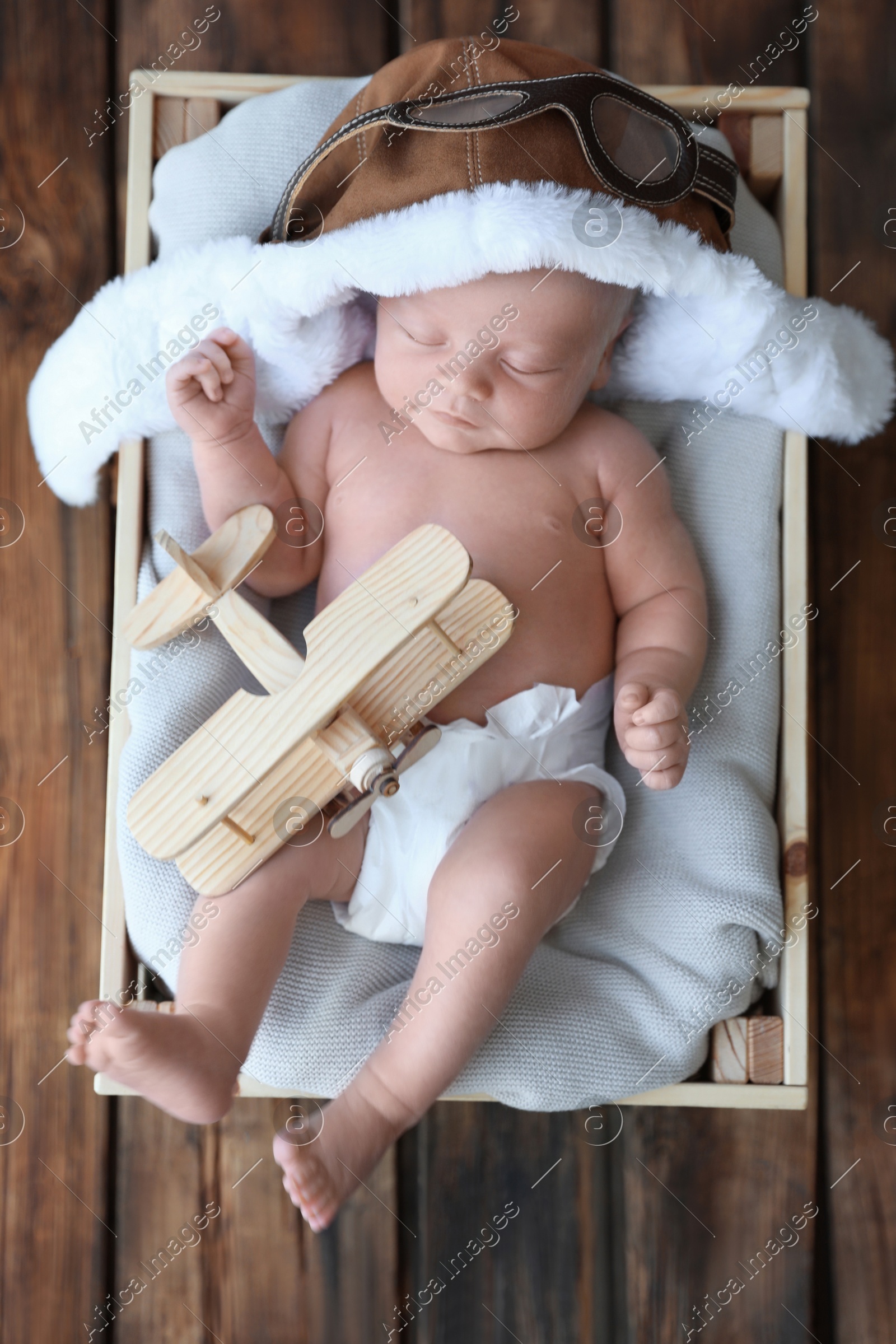 Cute newborn baby wearing aviator hat in wooden crate, top view Photo of Cute newborn baby wearing aviator hat in wooden crate, top view