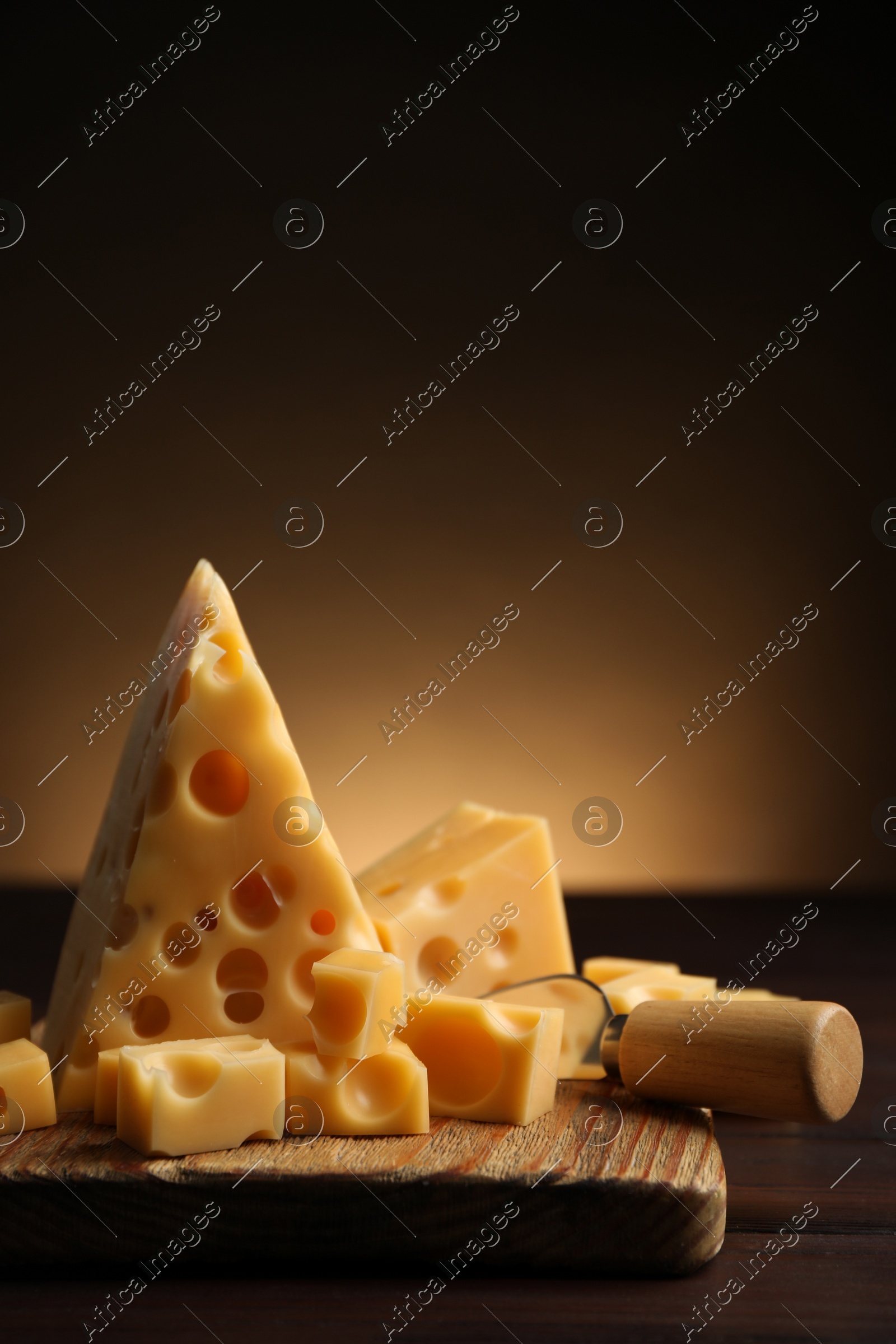 Pieces of delicious cheese and knife on wooden table. Space for text Photo of Pieces of delicious cheese and knife on wooden table. Space for text