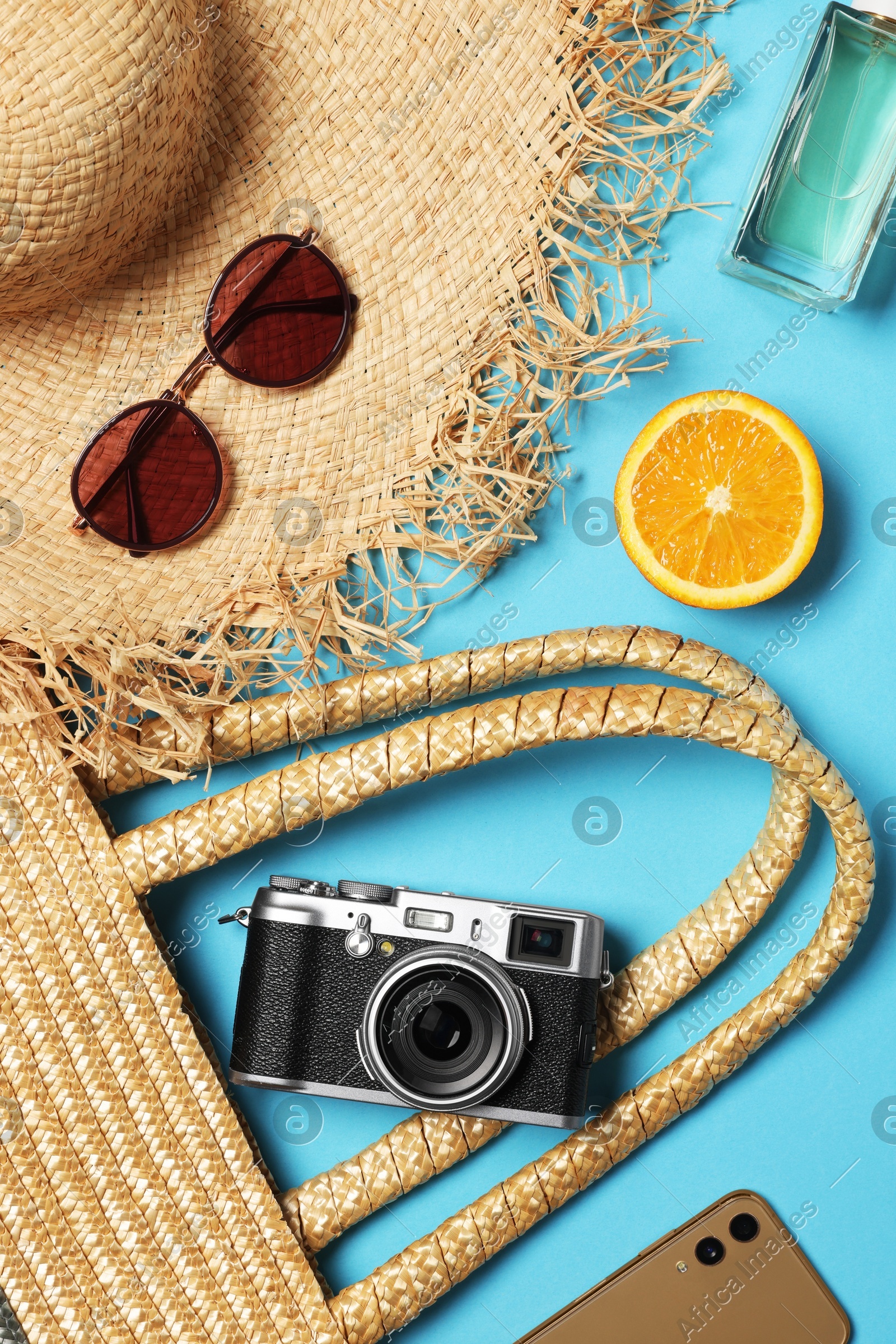 Flat lay composition with wicker bag and other beach accessories on light blue background Photo of Flat lay composition with wicker bag and other beach accessories on light blue background