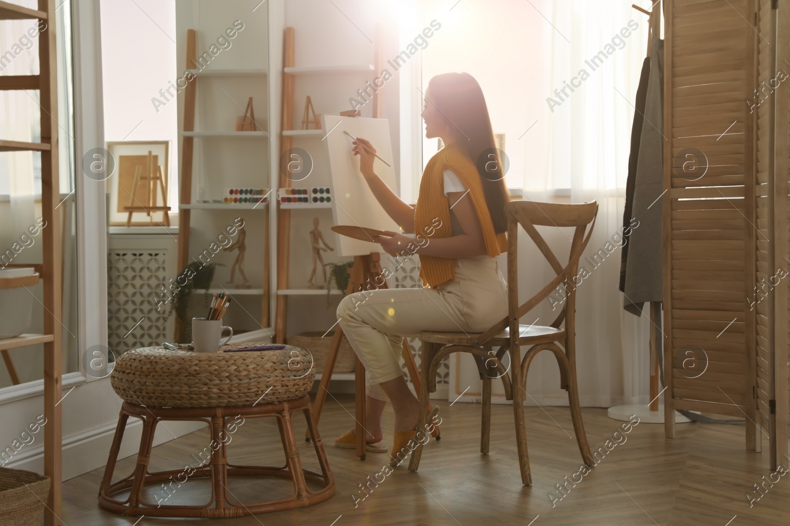 Beautiful young woman drawing on easel at home Photo of Beautiful young woman drawing on easel at home