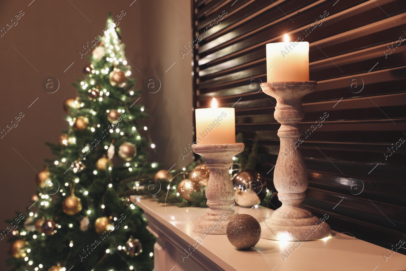 Burning candles and Christmas decor on white mantelpiece indoors Photo of Burning candles and Christmas decor on white mantelpiece indoors