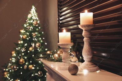 Burning candles and Christmas decor on white mantelpiece indoors Photo of Burning candles and Christmas decor on white mantelpiece indoors