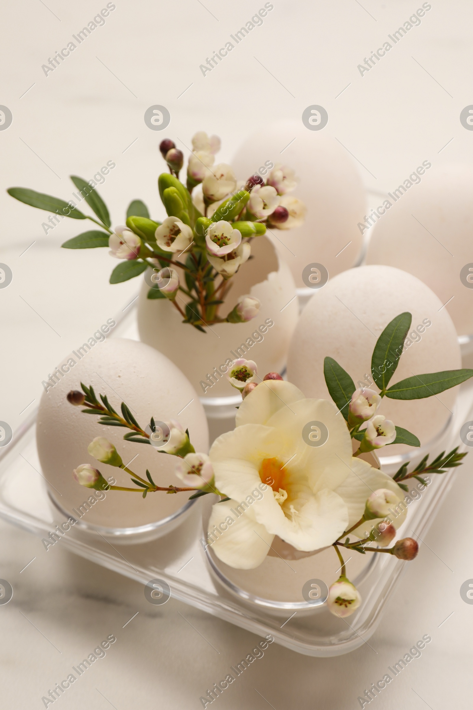 Easter eggs and beautiful flowers on white marble table, closeup Photo of Easter eggs and beautiful flowers on white marble table, closeup