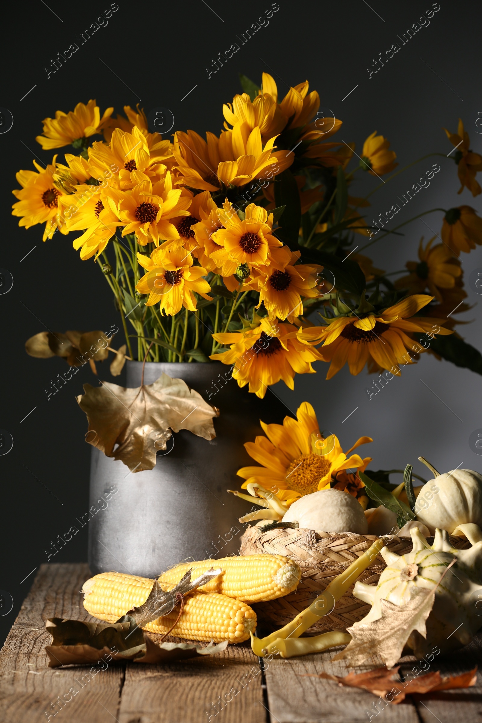 Beautiful autumn bouquet, small pumpkins and corn cobs on wooden table against dark grey background Photo of Beautiful autumn bouquet, small pumpkins and corn cobs on wooden table against dark grey background