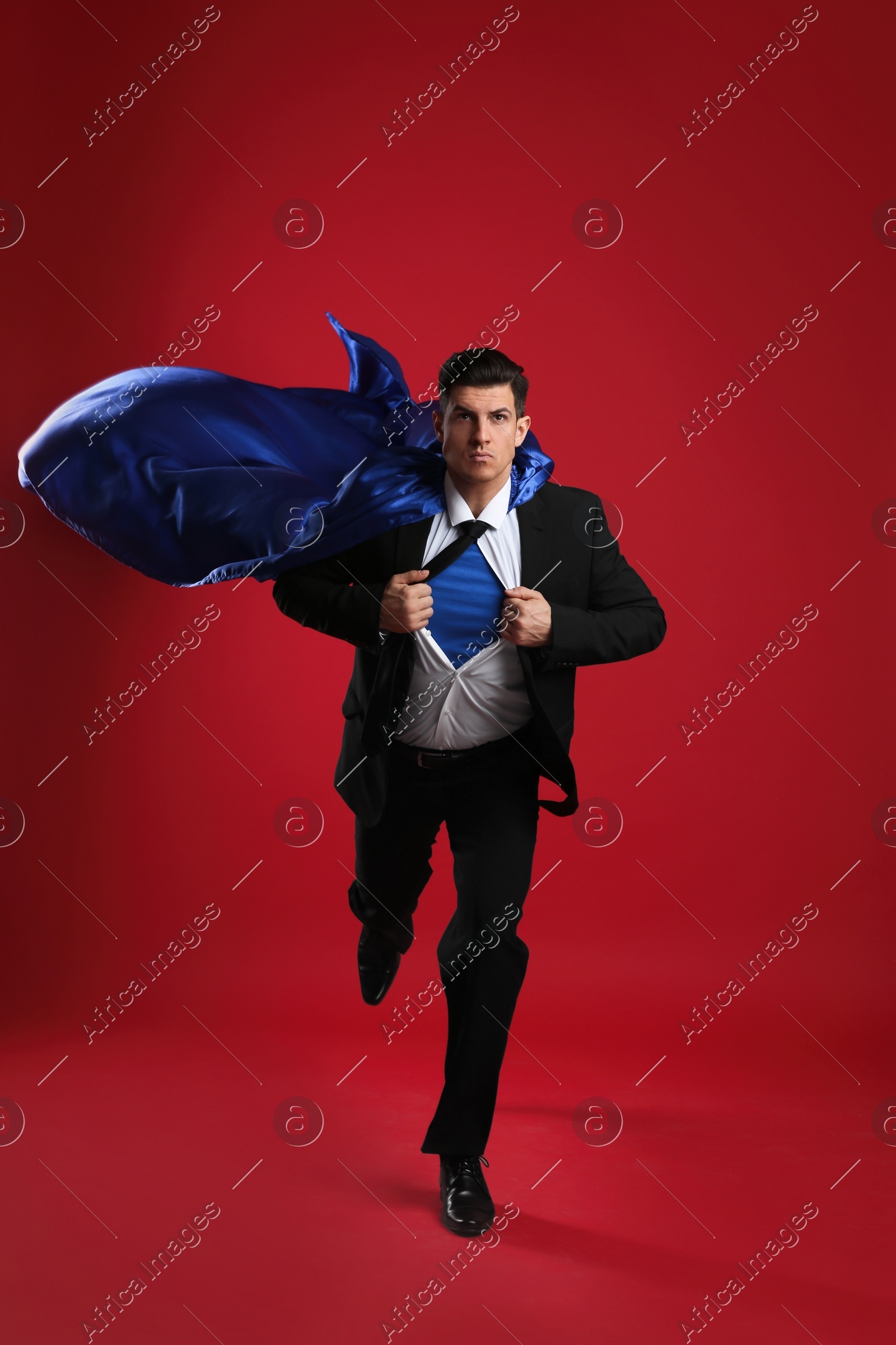 Man wearing superhero cape on red background Photo of Man wearing superhero cape on red background