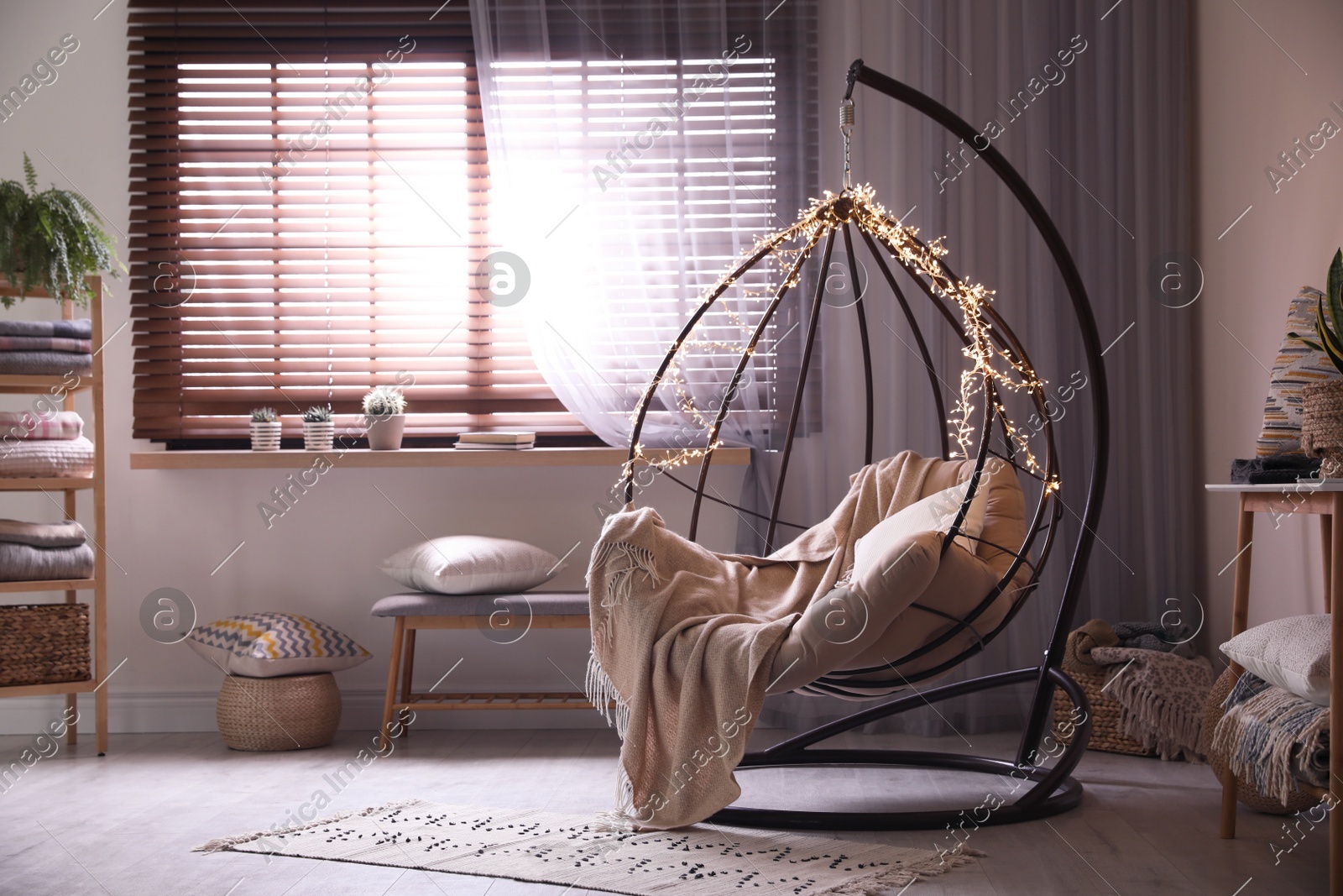 Cozy hanging chair with fairy lights in modern living room. Interior design Photo of Cozy hanging chair with fairy lights in modern living room. Interior design