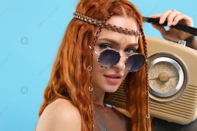 Stylish young hippie woman with retro radio receiver on light blue background Photo of Stylish young hippie woman with retro radio receiver on light blue background
