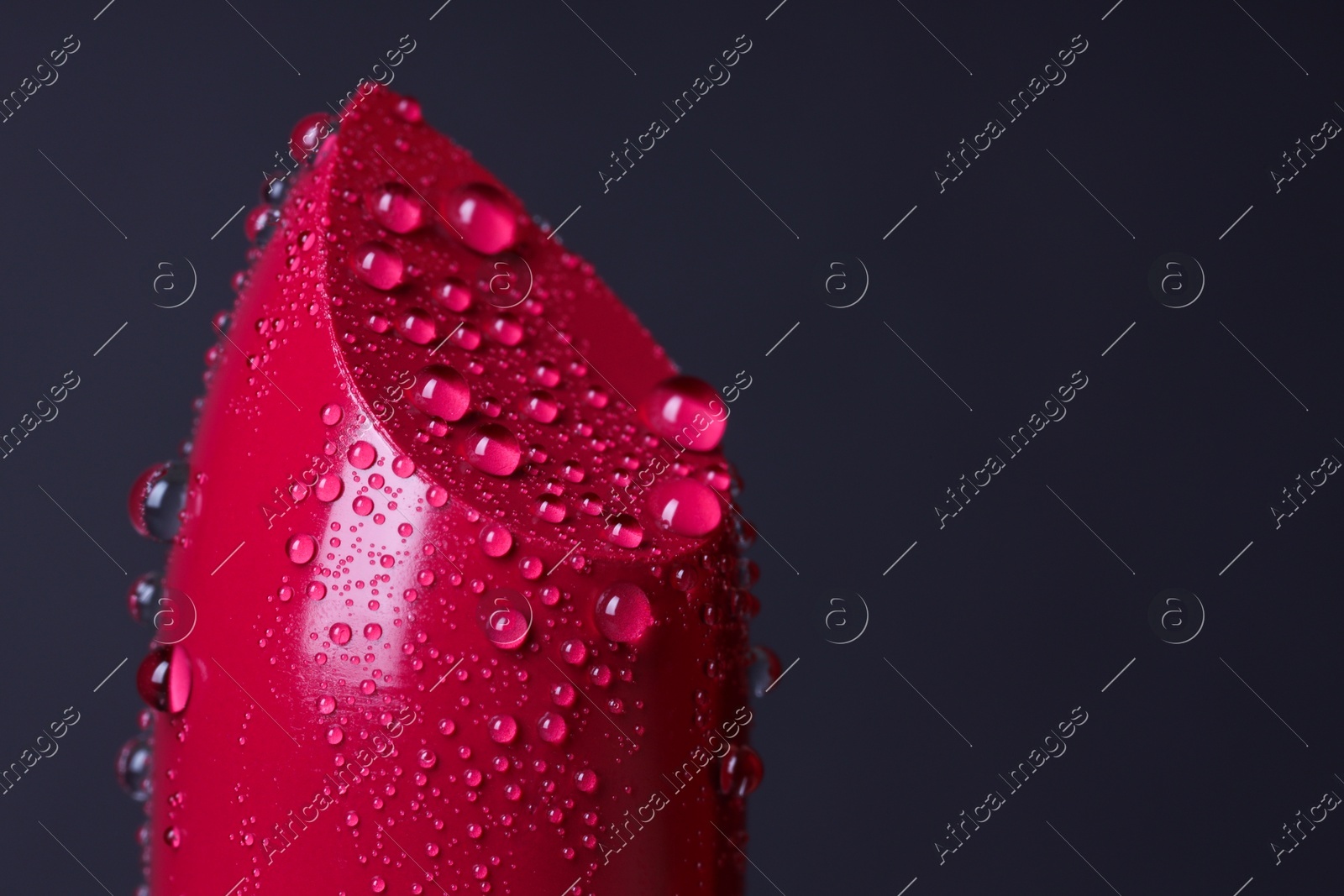 Red lipstick with water drops on dark gray background, macro view. Space for text Photo of Red lipstick with water drops on dark gray background, macro view. Space for text