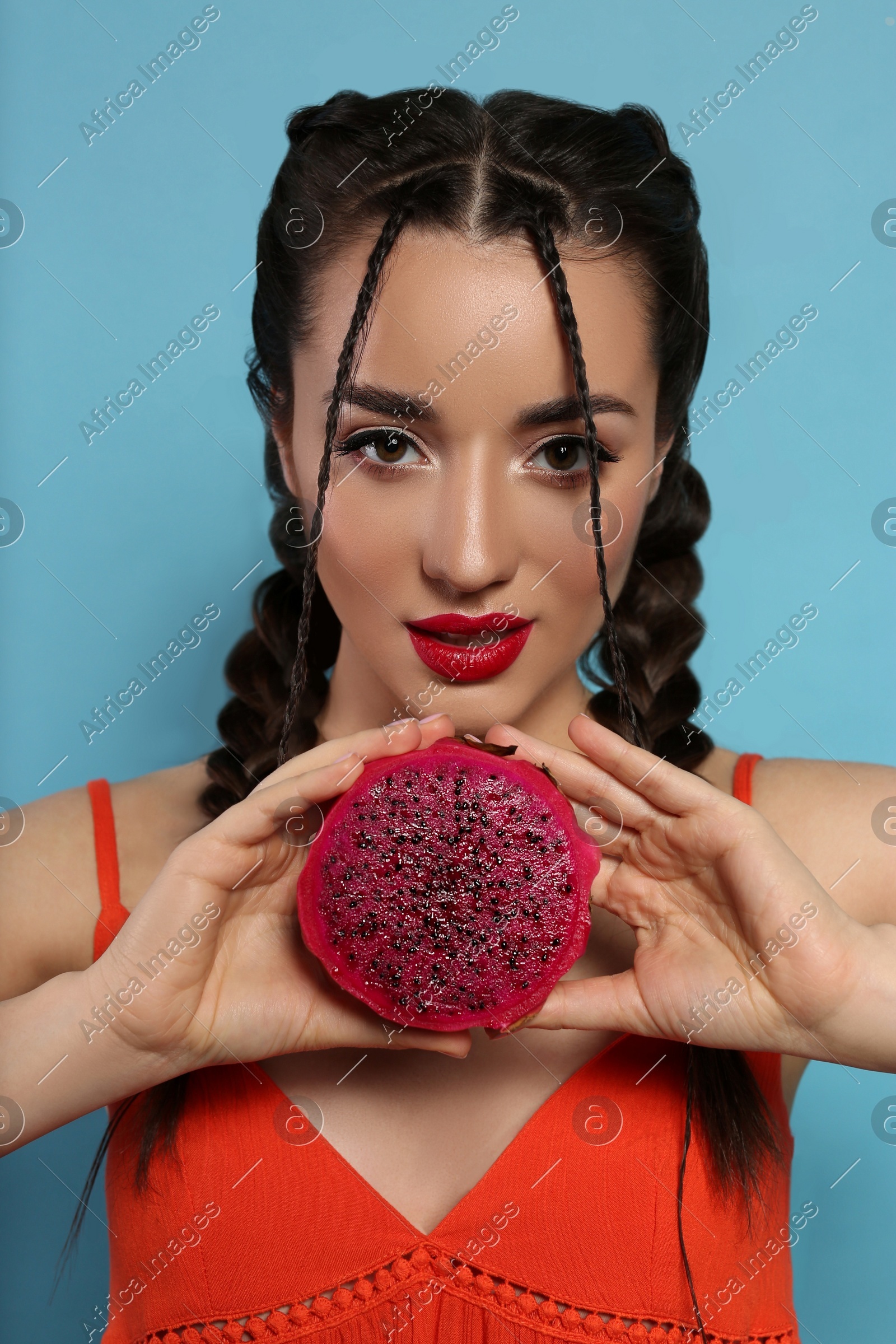 Young woman with fresh pitahaya on light blue background. Exotic fruit Photo of Young woman with fresh pitahaya on light blue background. Exotic fruit