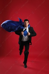 Man wearing superhero cape on red background Photo of Man wearing superhero cape on red background