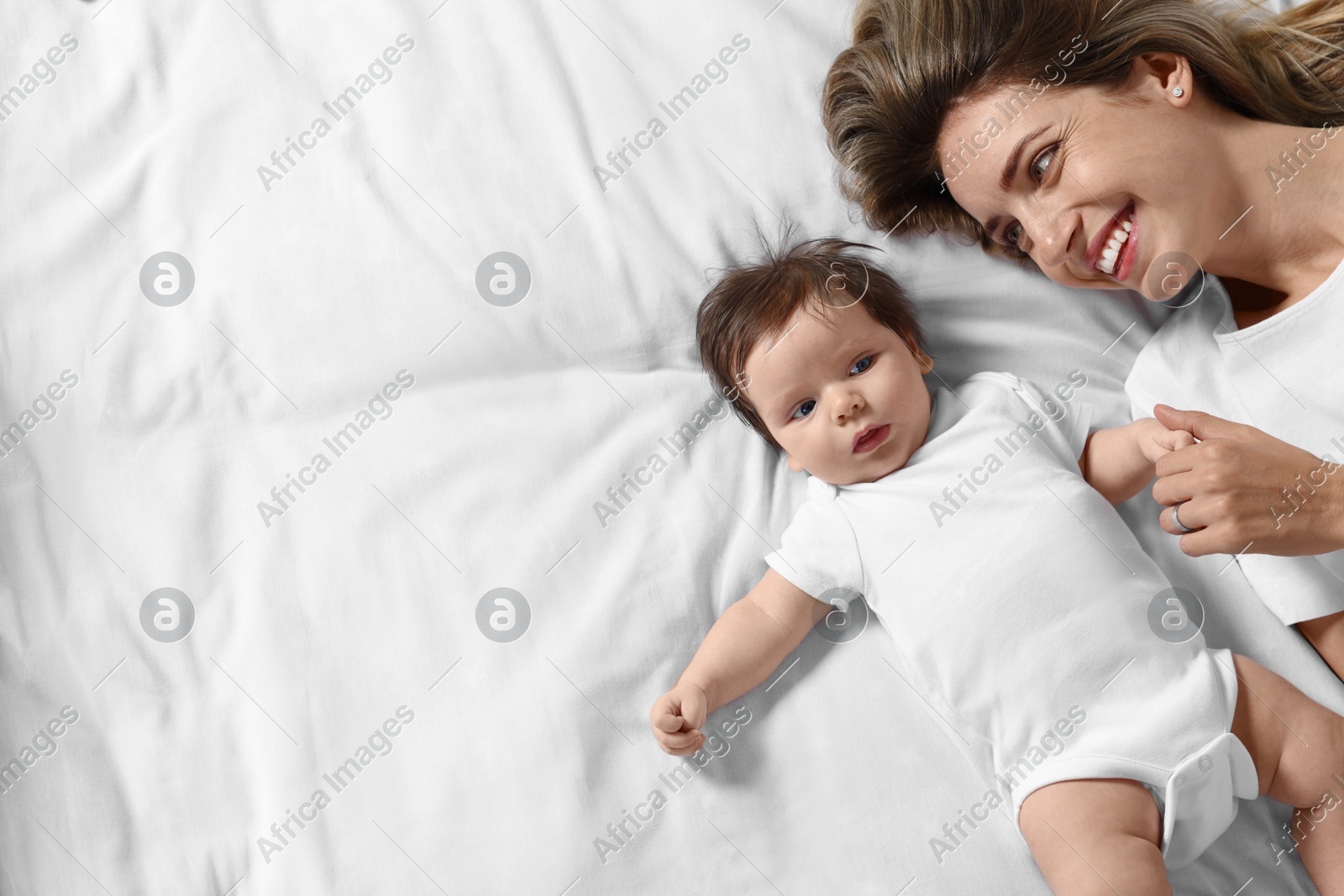 Mother and her little baby lying on bed, top view. Space for text Photo of Mother and her little baby lying on bed, top view. Space for text