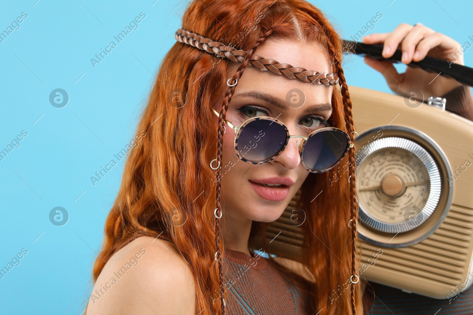 Stylish young hippie woman with retro radio receiver on light blue background Photo of Stylish young hippie woman with retro radio receiver on light blue background