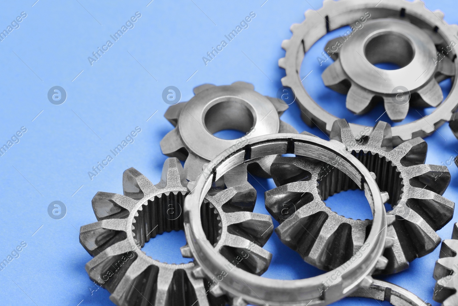 Different stainless steel gears on light blue background, closeup. Space for text Photo of Different stainless steel gears on light blue background, closeup. Space for text