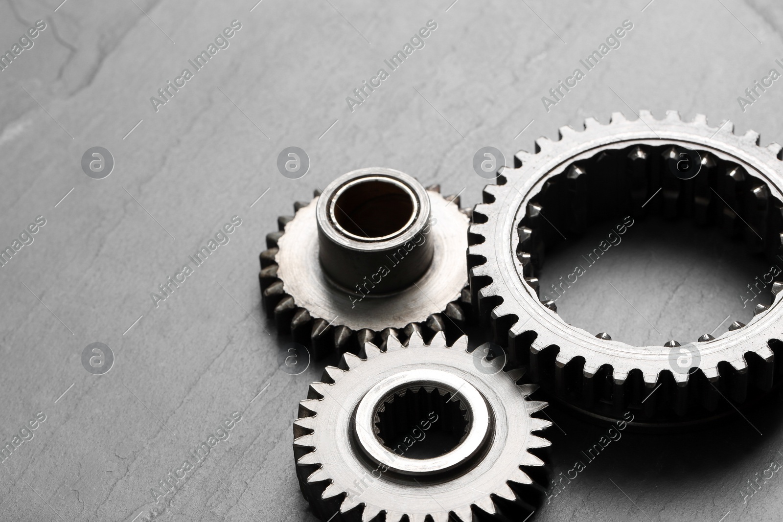 Different stainless steel gears on grey background, space for text Photo of Different stainless steel gears on grey background, space for text